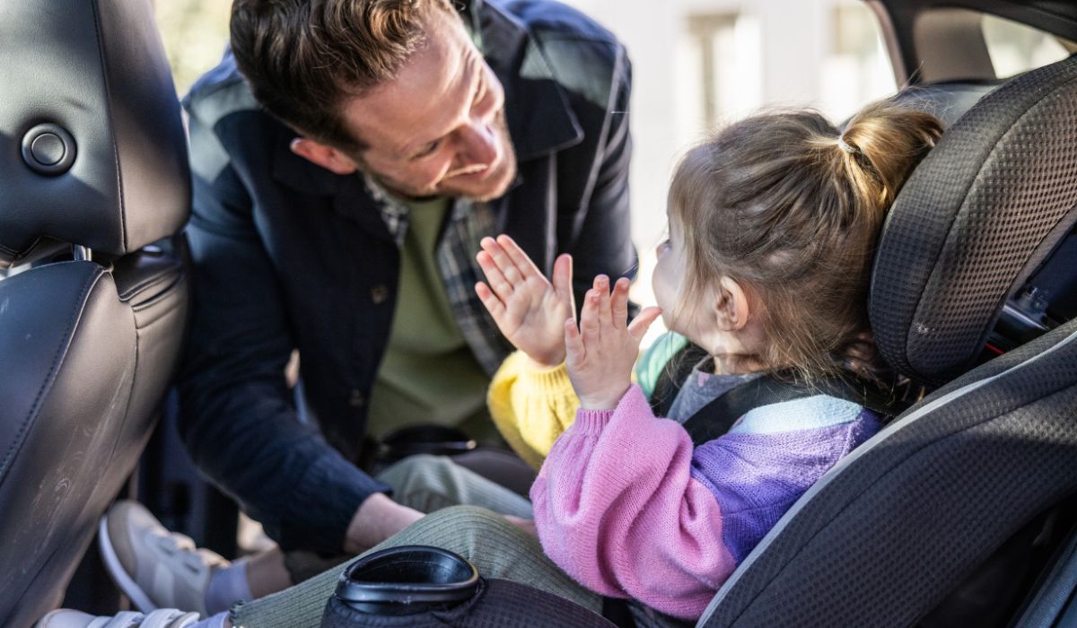 Dad putting his child in a car seat