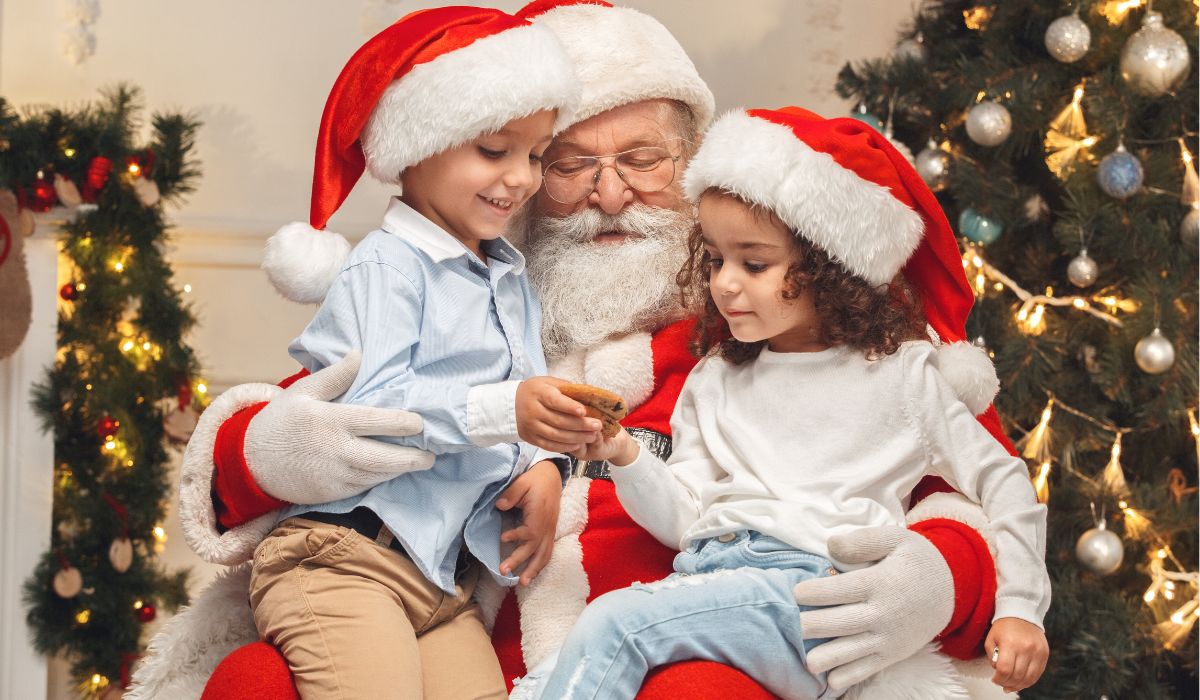 Two kids a boy and a girl sitting on Santa's lap