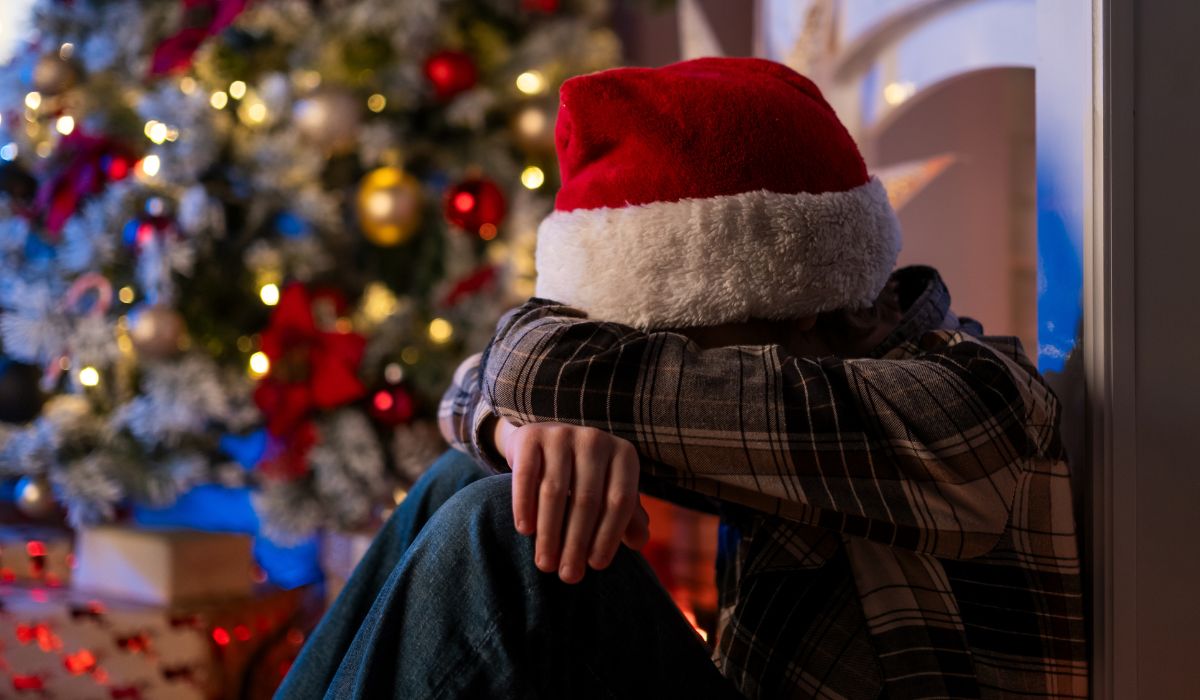 Young boy sitting his his head in his arms at Christmas
