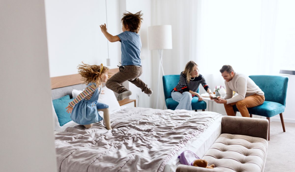 Family in hotel room, children jumping on the bed