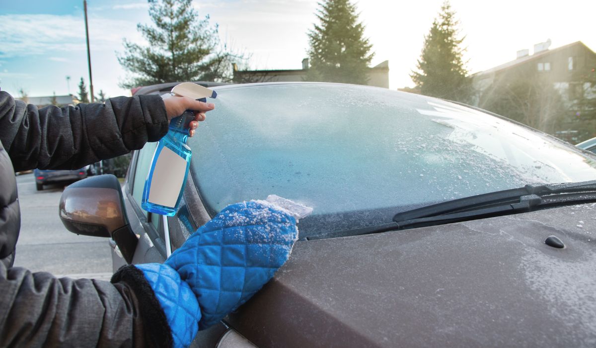 Man spraying solution on icy car windscreen