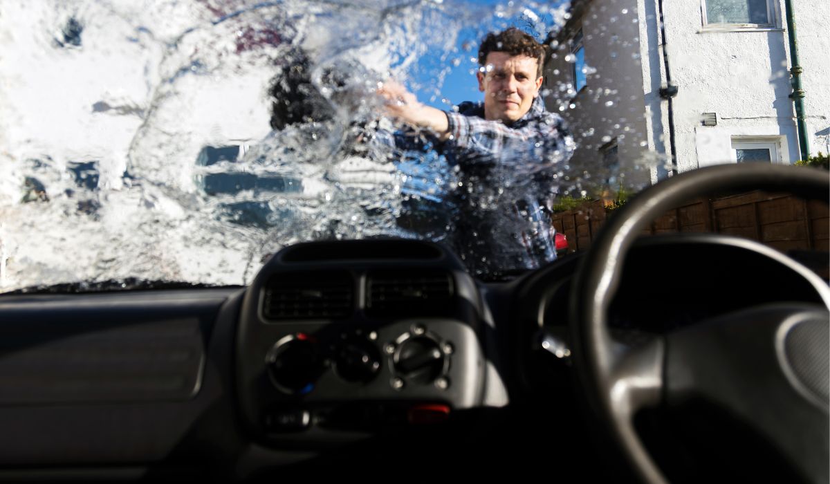 Man throwing water on car windscreen