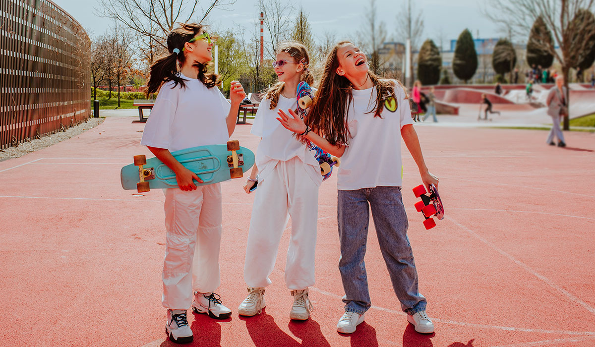 Teenage friends with skateboard spending leisure time at playground