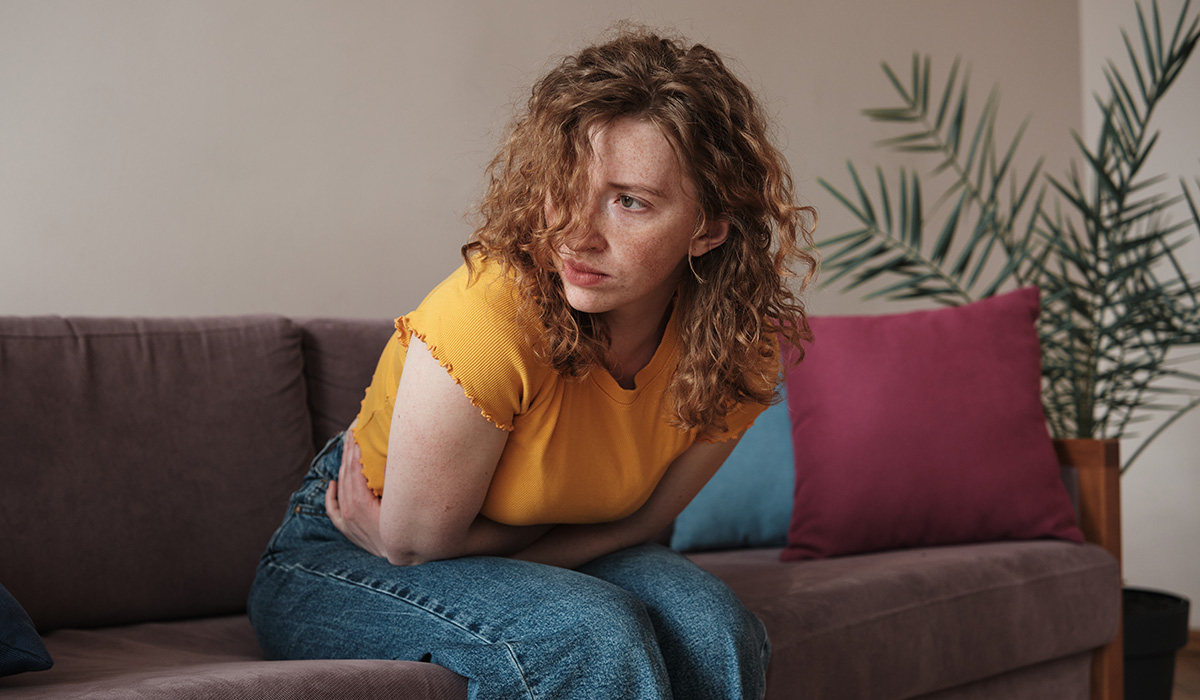 PMS symptoms. Young woman touching belly suffers from stomachache at home
