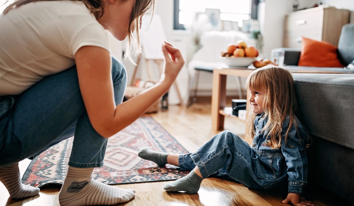 Mother scolding little girl who is sitting on the floor