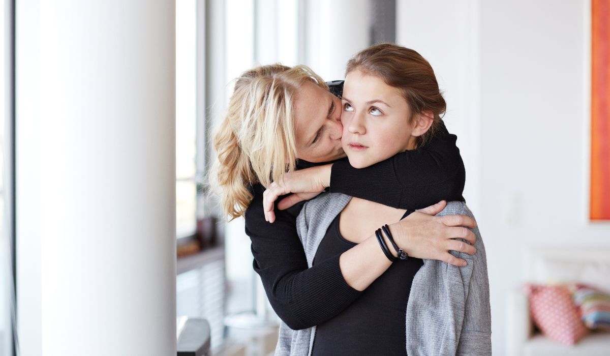 Mother hugging embarrassed daughter