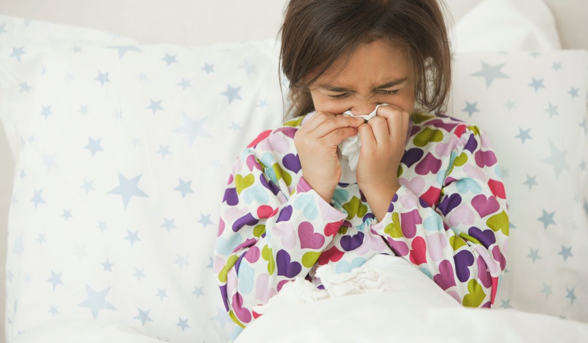 Girl with the flu in bed blowing nose