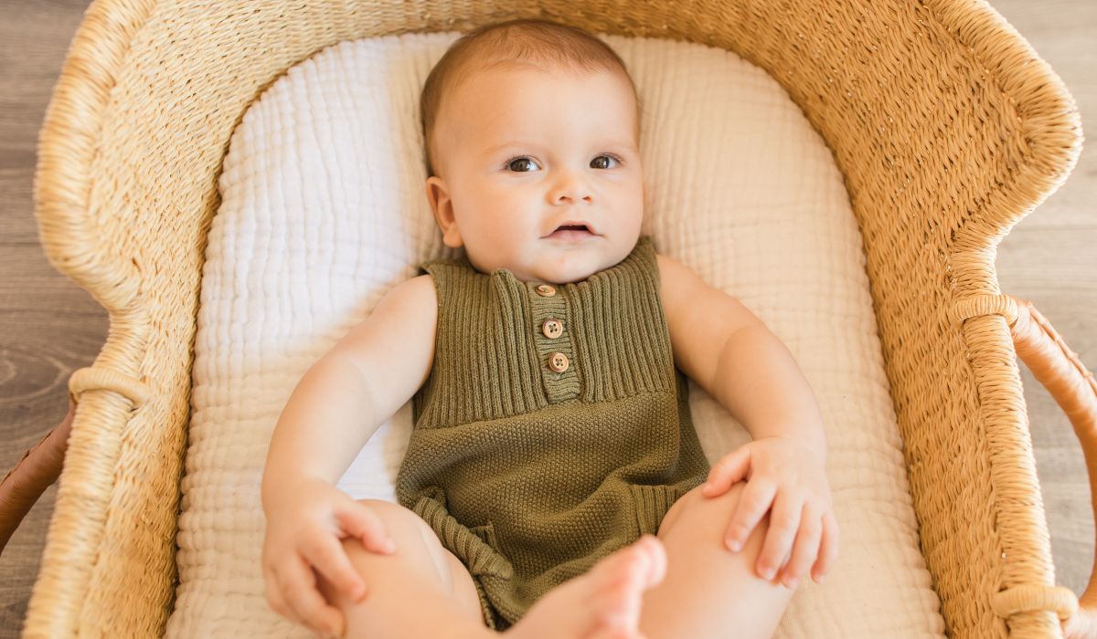 Baby dressed in green in it's bassinette