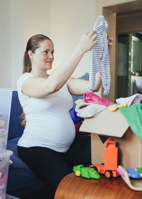 Woman sorting used baby clothes at home.