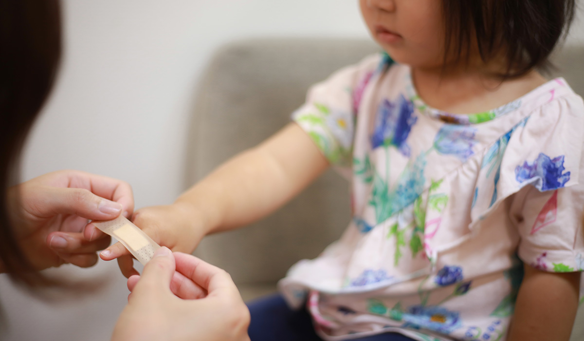 Little girl with a plaster being put on her finger