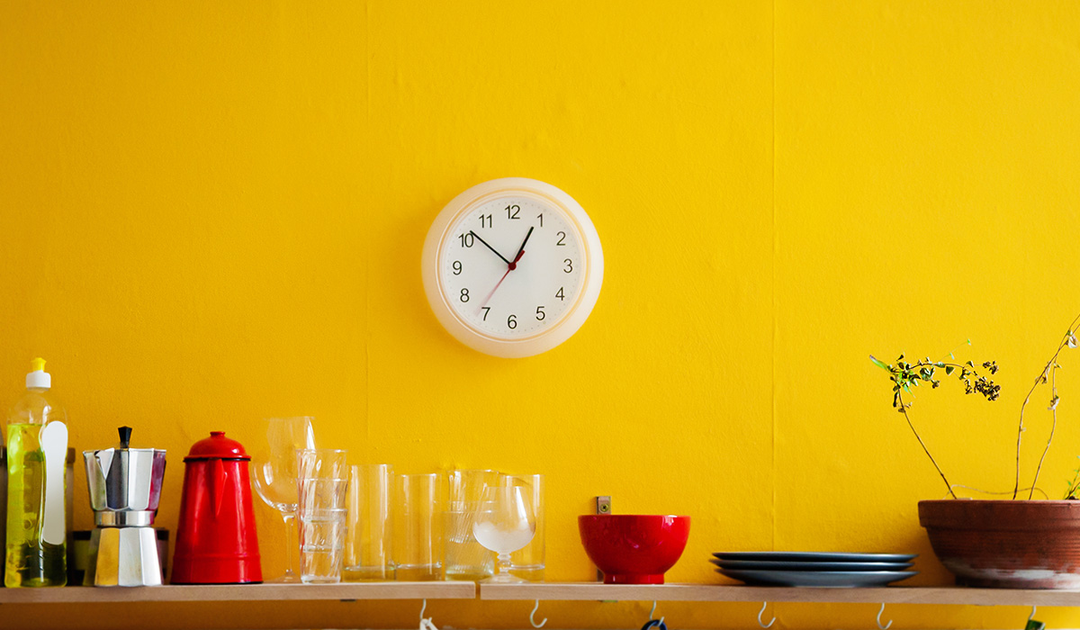 Yellow wall with utensils on a shelf and wall clocks