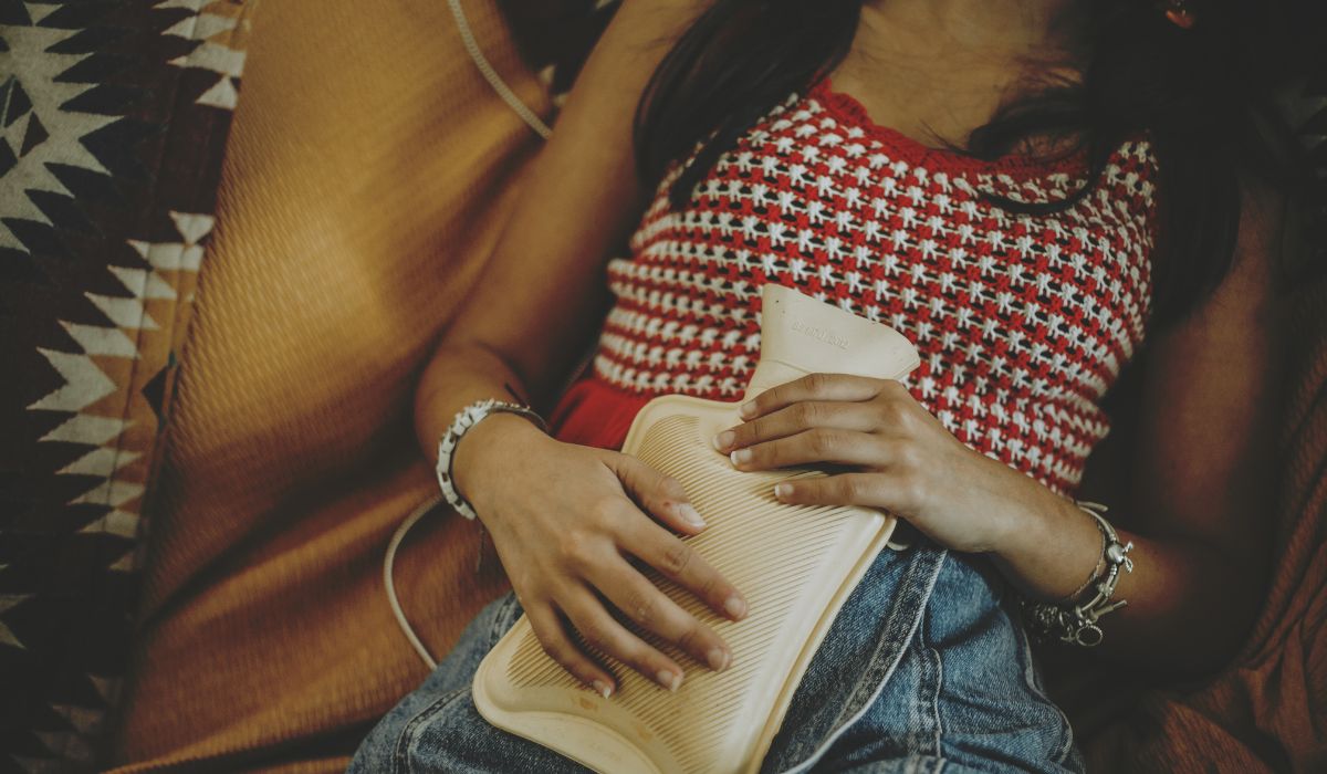Woman holding hot water bottle over stomach