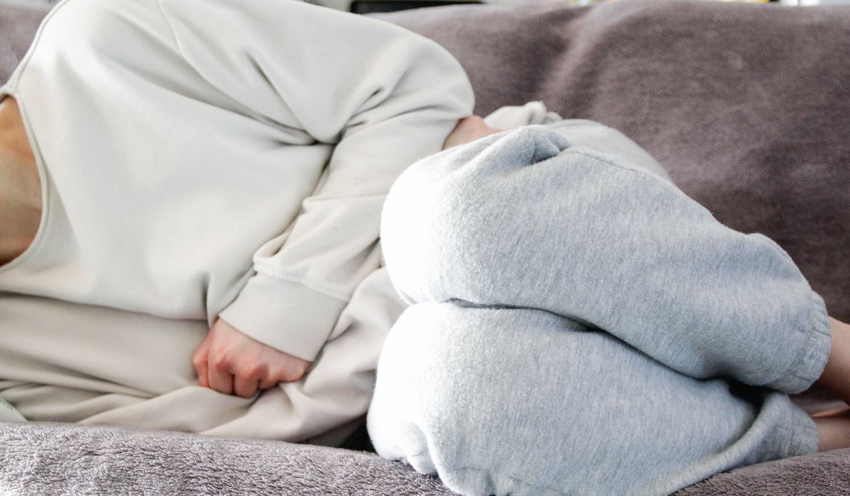 Woman on couch with stomach pain.