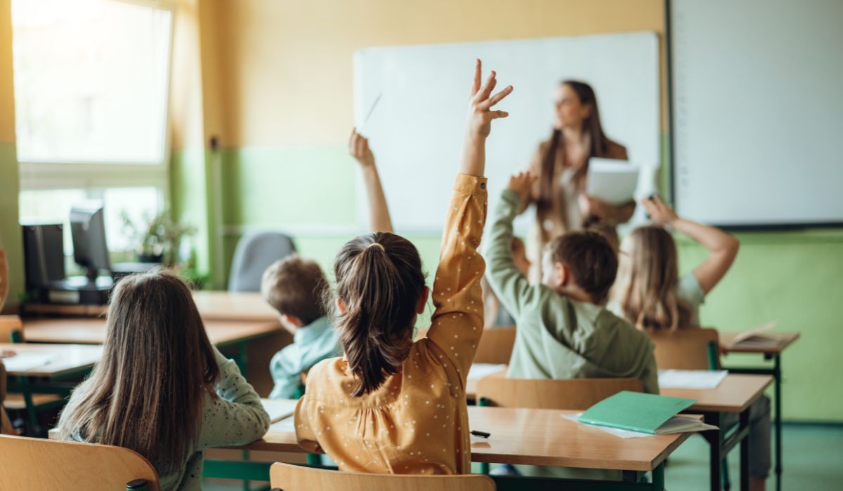 Kids putting their hands up in school