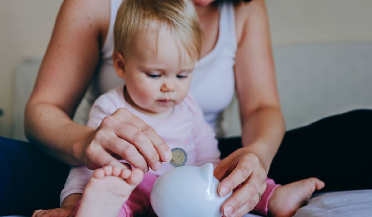 Little girl putting money in a money bank