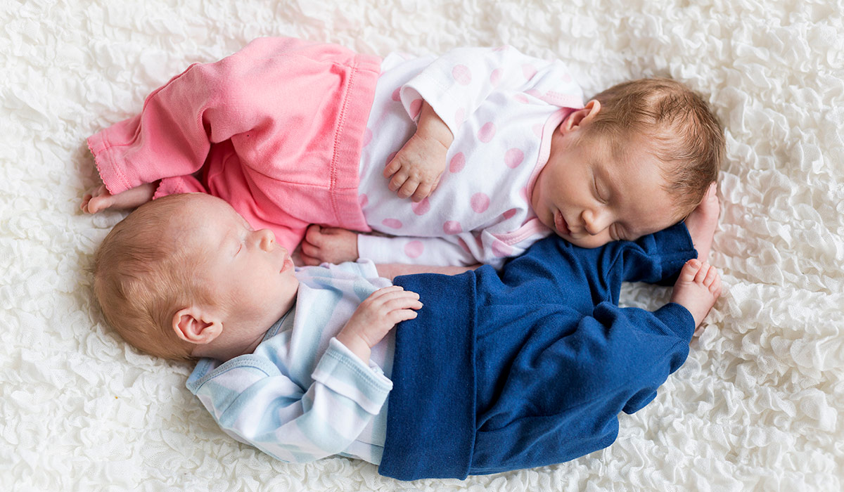 Newborn twins sleeping on white blanket