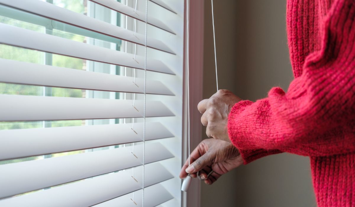 Woman pulling window blind cords