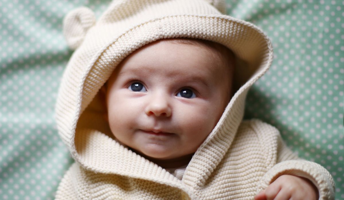 Cute baby wearing hood with teddy bear ears.