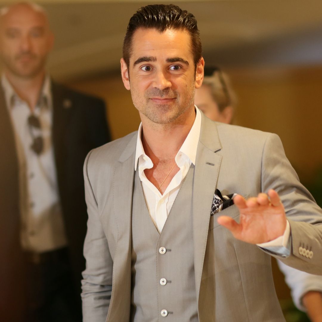 Colin Farrell in a suit waving at fans