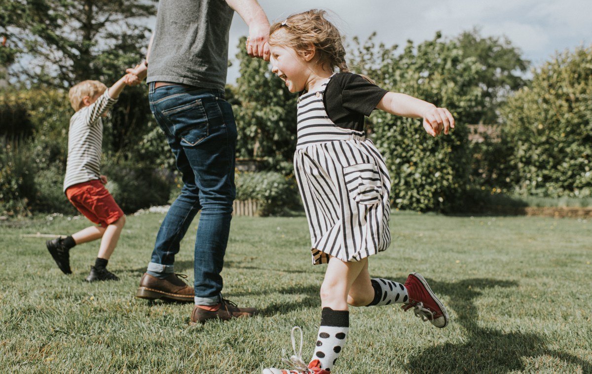 Kids running around the garden with their dad