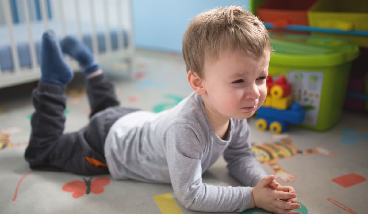 Young boy lying on the floor crying