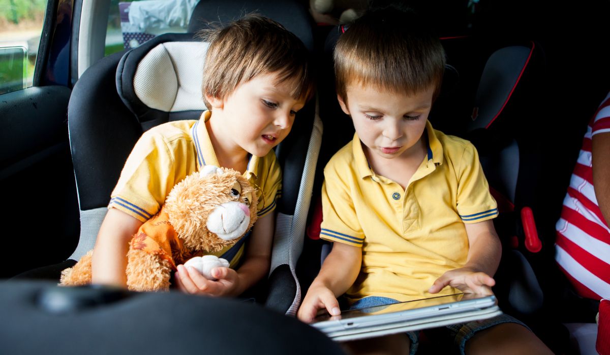 To boys looking at a book in their car seats