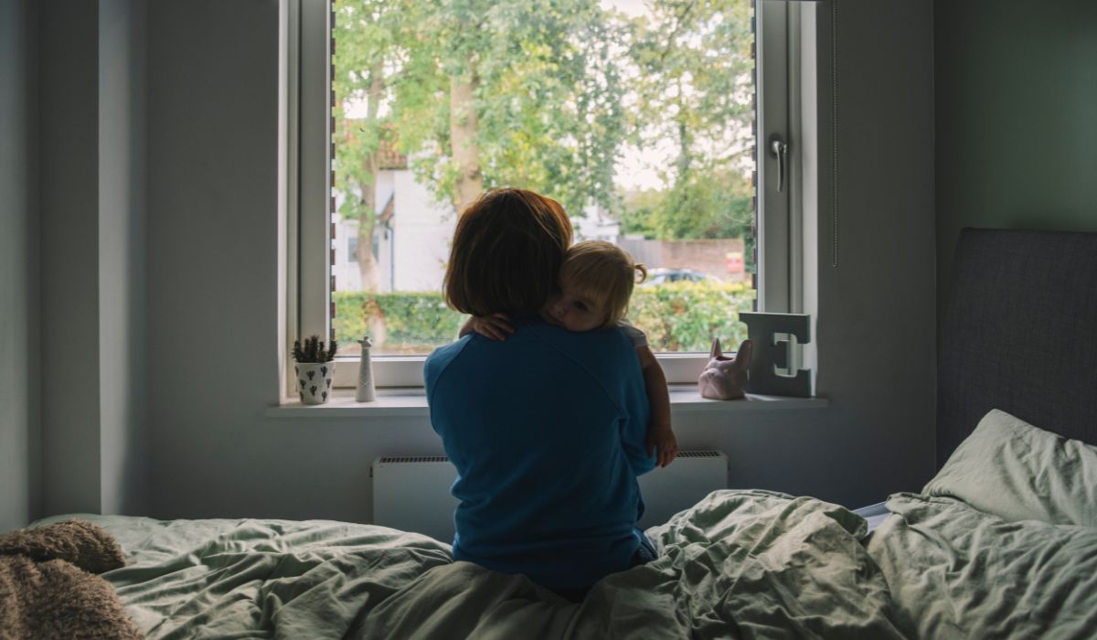 Mother hugging child in bedroom