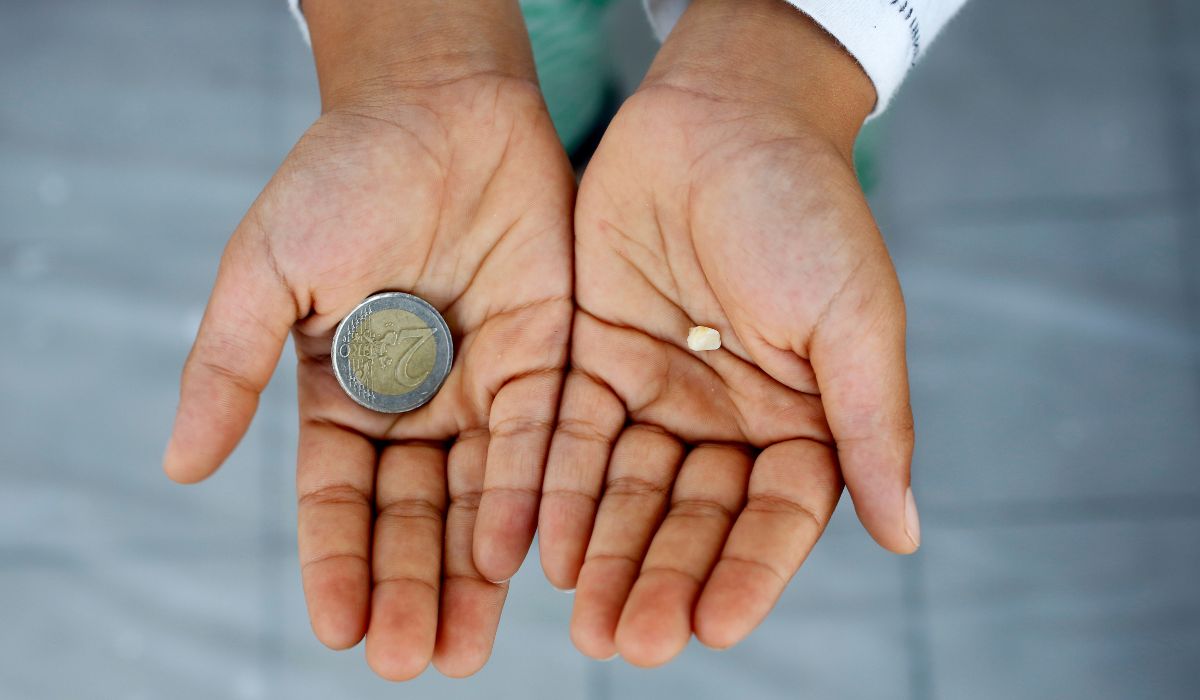 Child holding a tooth in one hand and €2 in the other