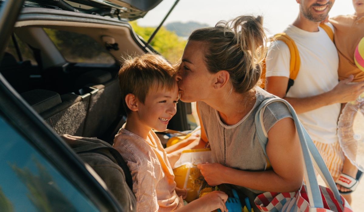 Mother kissing little boy in car