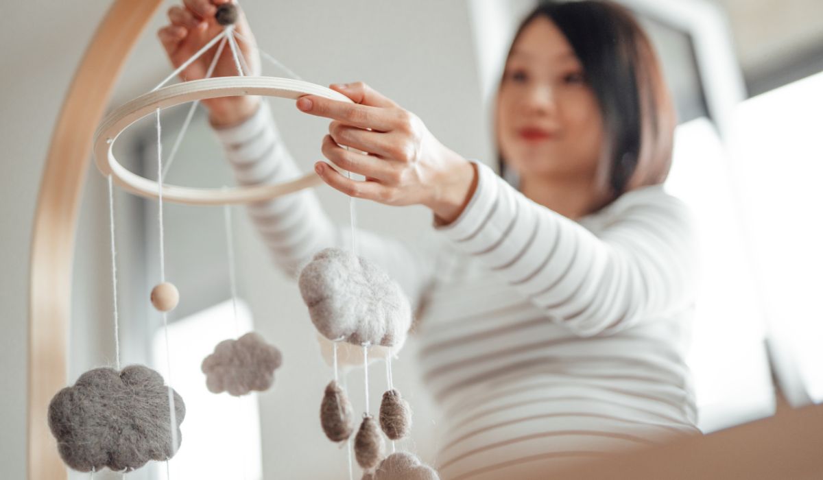Woman looking at a mobile above a baby's cot
