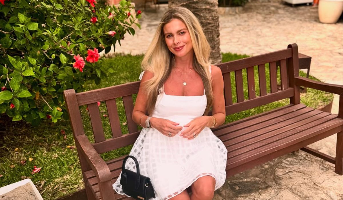 Jess Redden in a white dress sitting on a bench