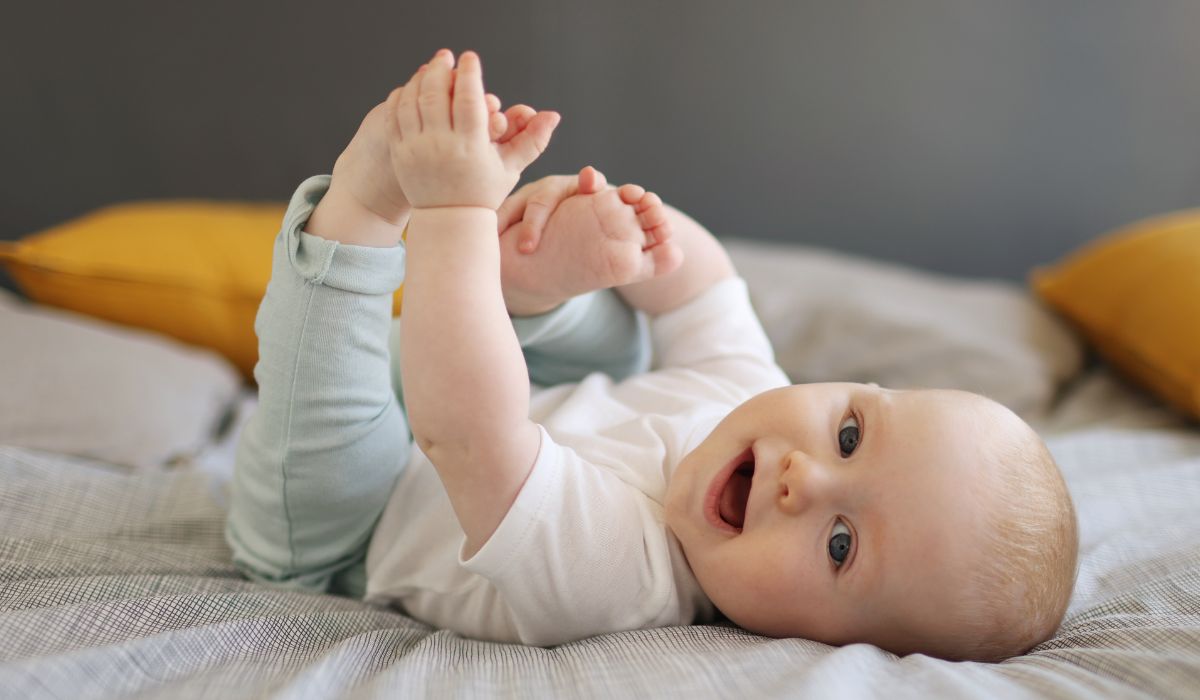 Baby touching toes while lying in a bed