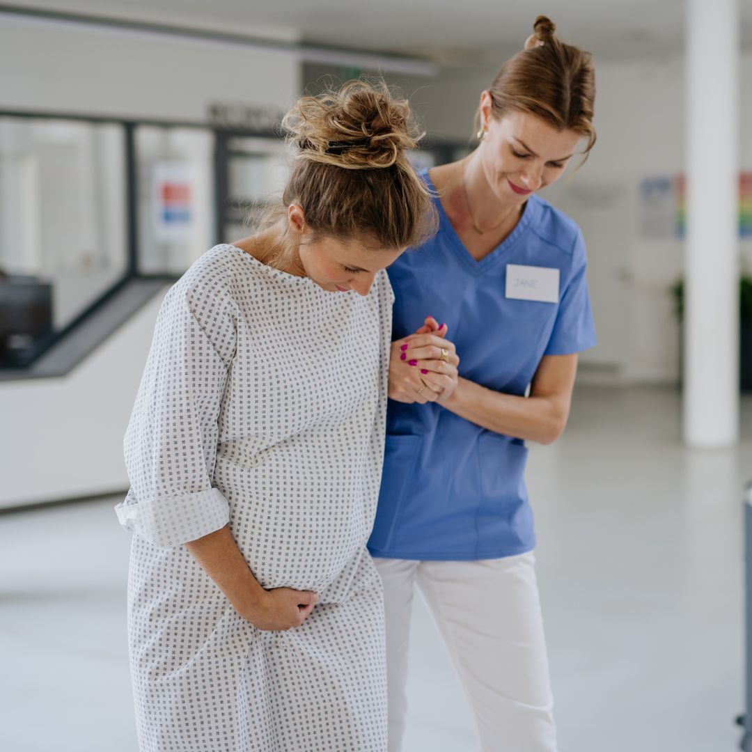 Woman walking through hospital with midwife in labour