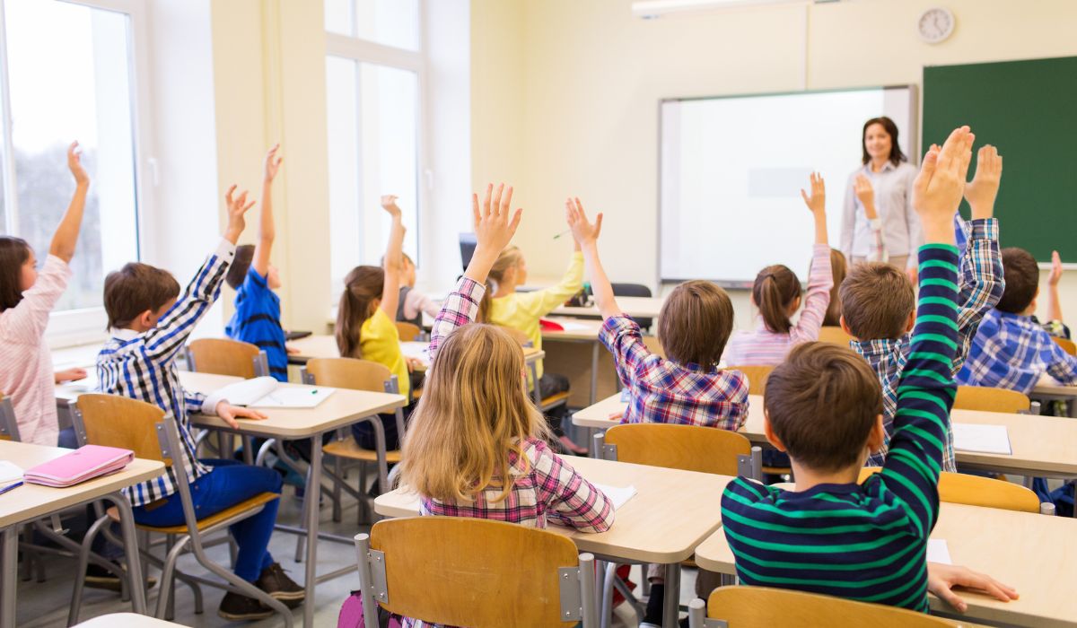 Teacher in class with kids raising their hands