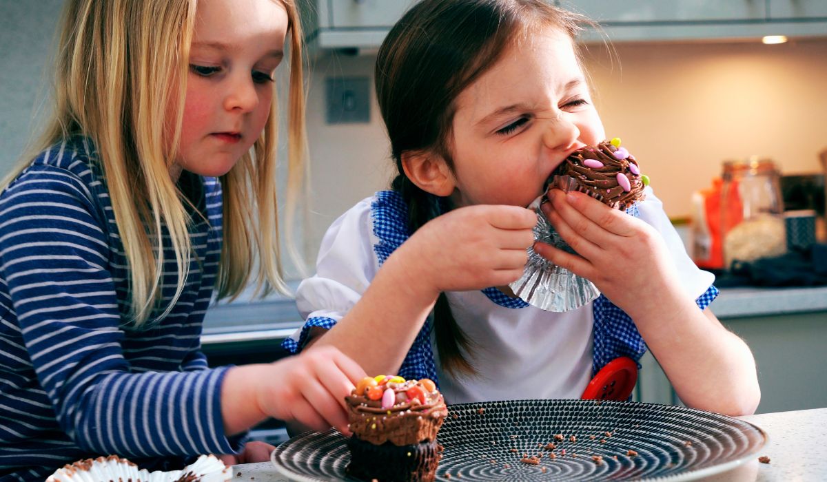 Two young girls eating chocolate cupcakes