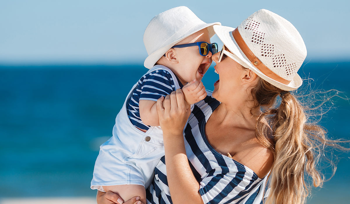 Happy family relaxing by the sea. Happy family resting at beach in summer. mother with baby boy resting on the beach. Young mother and her adorable little daughter on beach vacation;