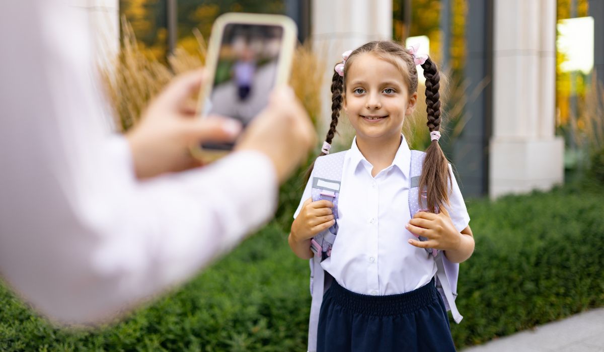 Mother taking a photo of her daughter on her first day of school