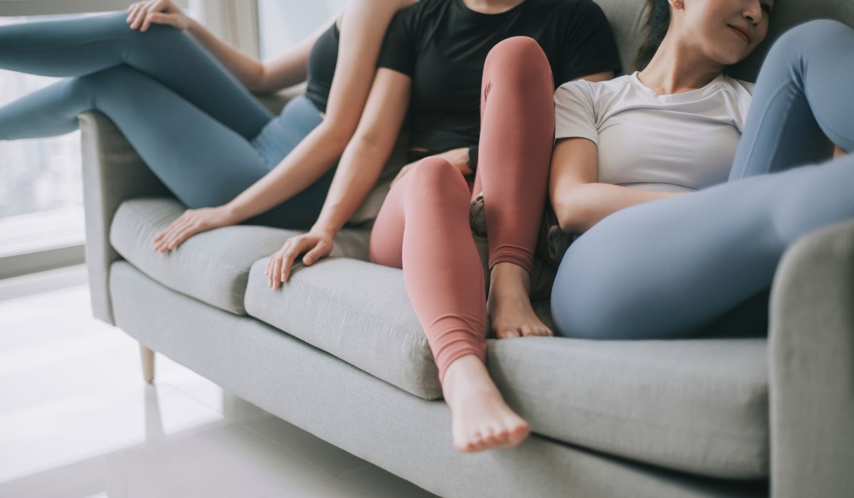 Group of women wearing yoga clothing sitting on sofa posing in living room