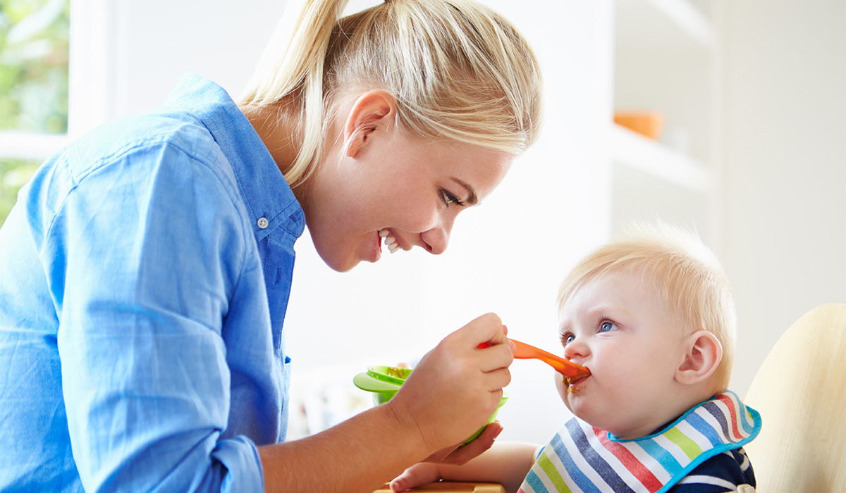 Mother Feeding Baby Boy In High Chair; Shutterstock ID 177222584; purchase_order: -; job: -; client: -; other: -