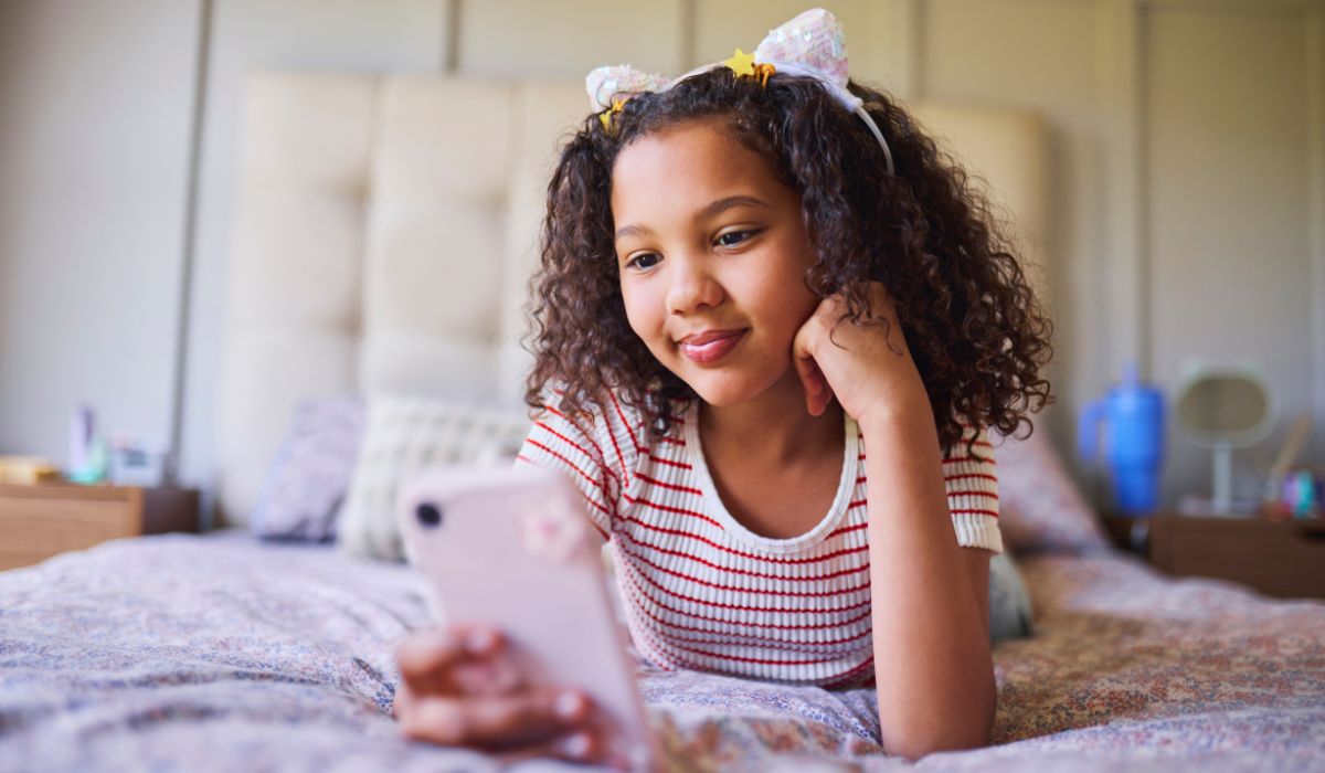 Little girl wearing cat ears looking at phone