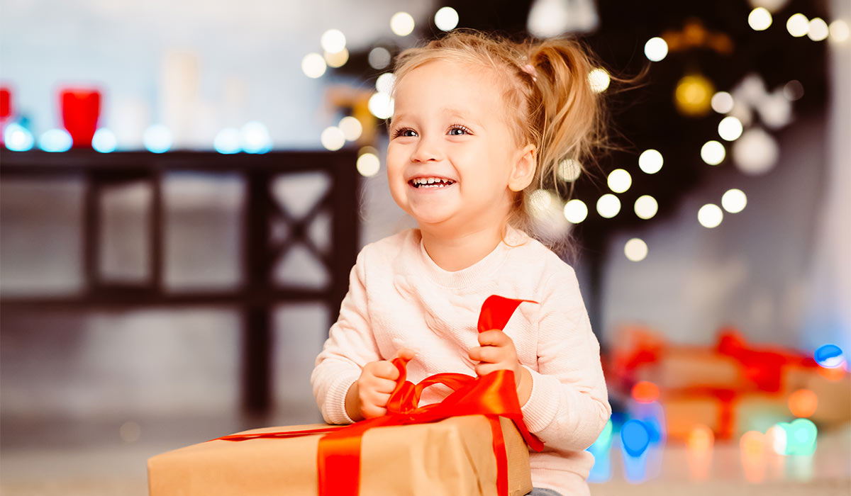 Cute happy little girl opening Christmas gift at home, empty space; Shutterstock ID 1571420971; purchase_order: -; job: -; client: -; other: