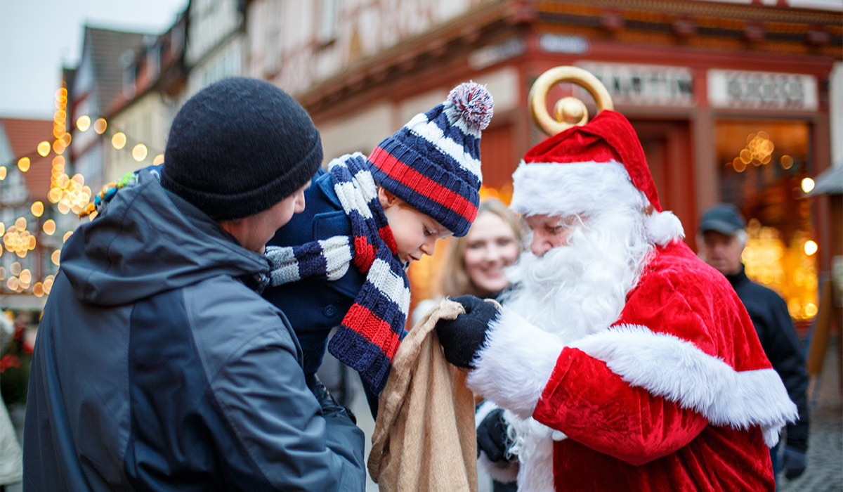 Little toddler boy with father on Christmas market. Happy kid taking gift from Santa Claus. Smiling man and son, family celebrating traditional holiday; Shutterstock ID 2359205609; purchase_order: -; job: -; client: -; other: