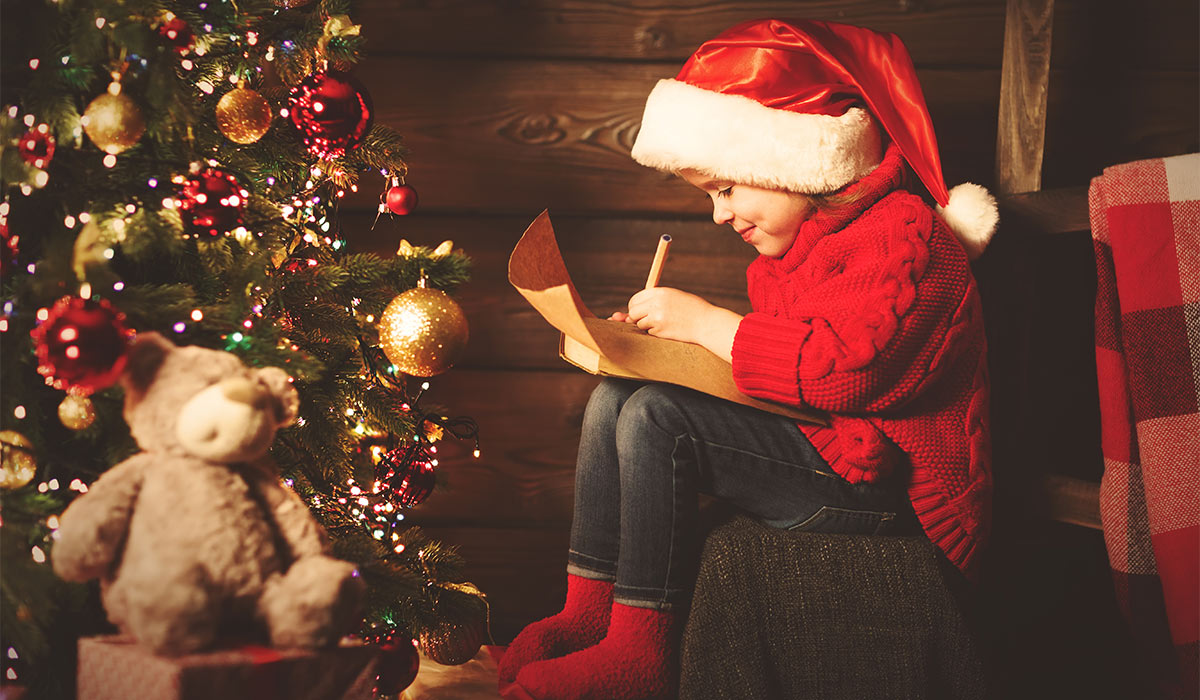 happy child girl writes letter to Santa Claus at the Christmas tree in the evening; Shutterstock ID 519952294; purchase_order: -; job: -; client: -; other: