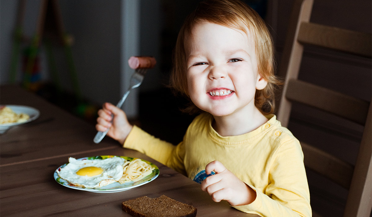 Cute toddler boy eating sausage and eggs for Breakfast.; Shutterstock ID 598327784; purchase_order: -; job: -; client: -; other: