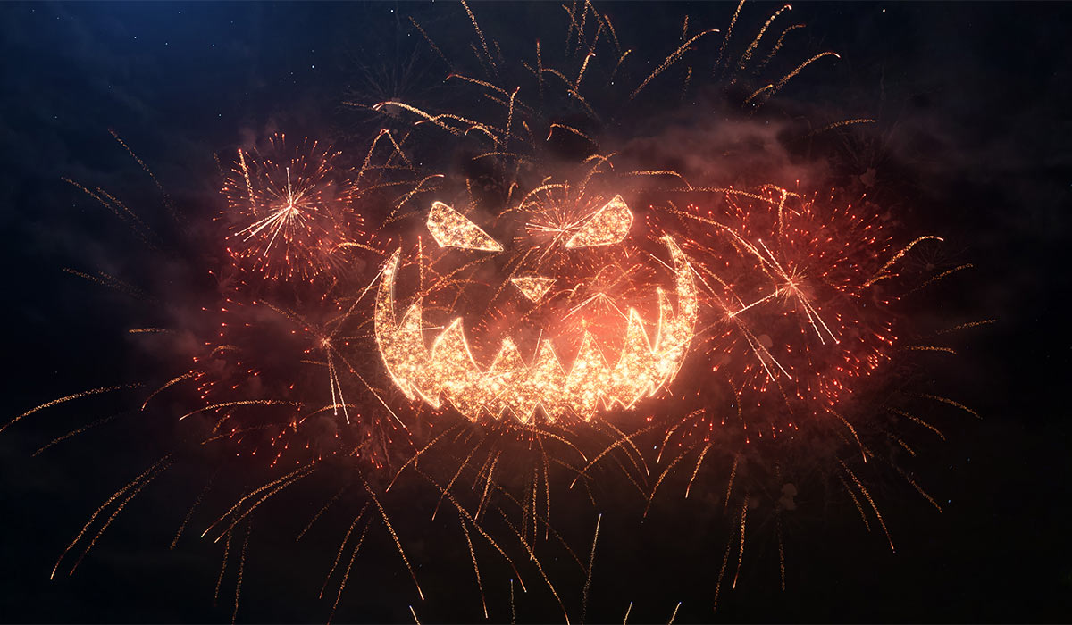 Happy Halloween greeting pumpkin with particles and sparks on black night sky with colored slow motion fireworks on background, beautiful typography magic design.