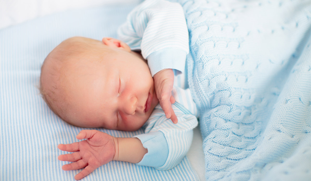 Newborn baby boy in bed. New born child sleeping under a blue knitted blanket. Children sleep. Bedding for kids. Infant napping in bed. Healthy little kid shortly after birth. Cable knit textile.; Shutterstock ID 2475656905; purchase_order: -; job: -; client: -; other: