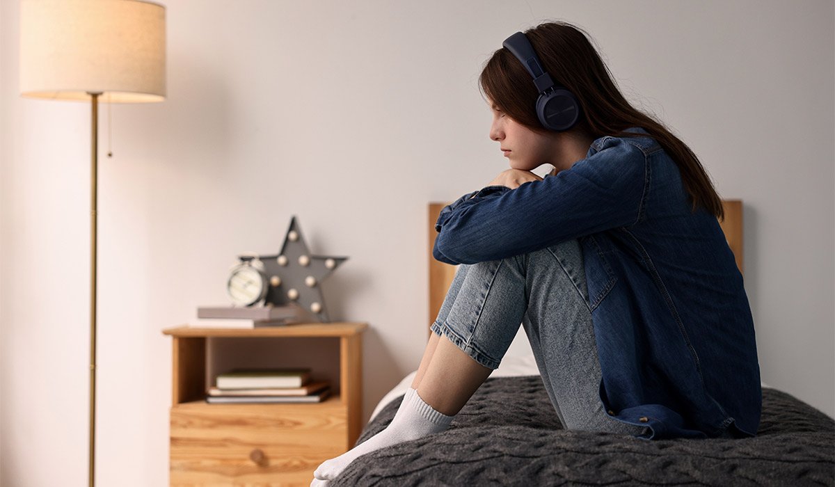 Loneliness concept. Sad teenage girl in headphones listening to music on bed at home; Shutterstock ID 2530310675; purchase_order: -; job: -; client: -; other: