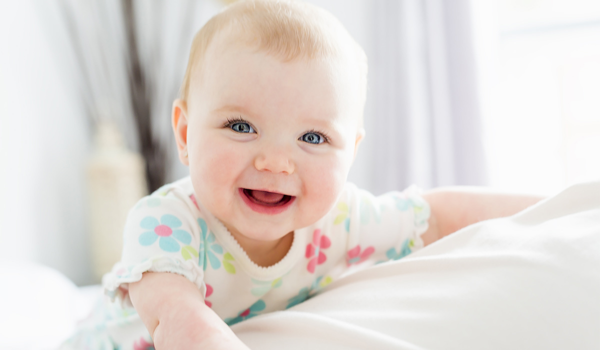 A Baby girl in white bedding at home look nice