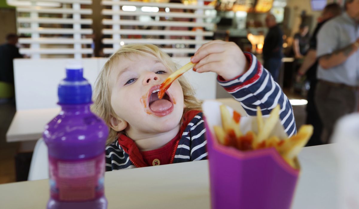 Child eating chips with ketchup