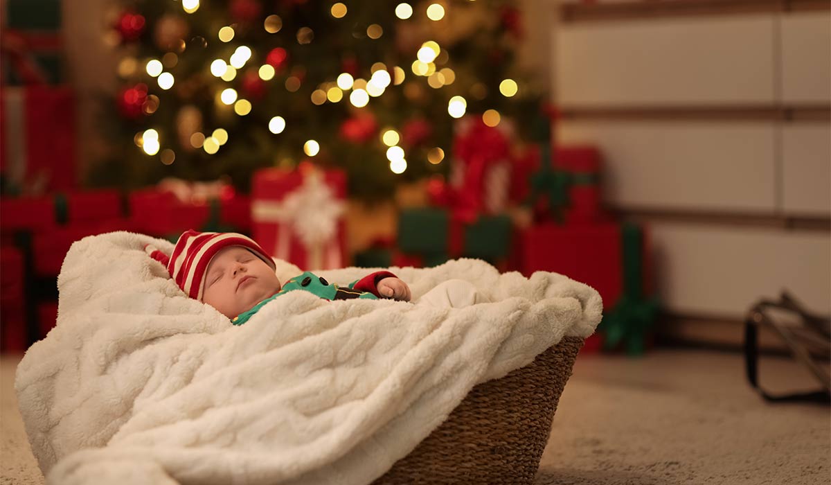 Cute little baby dressed as elf sleeping in basket near Christmas tree at night; Shutterstock ID 2704367359; purchase_order: -; job: -; client: -; other: